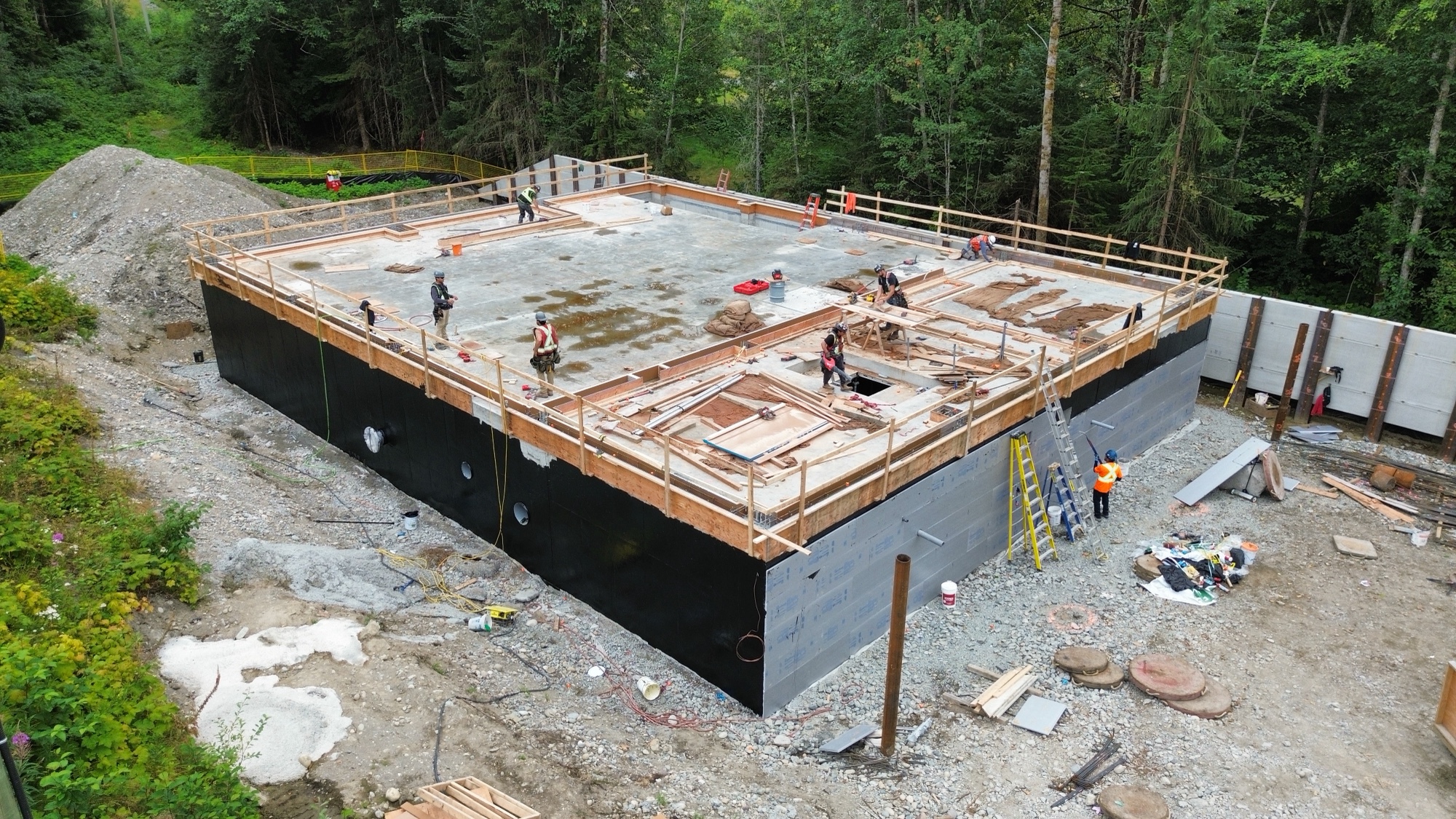 Looking down at a concrete structure with workers walking on the roof.