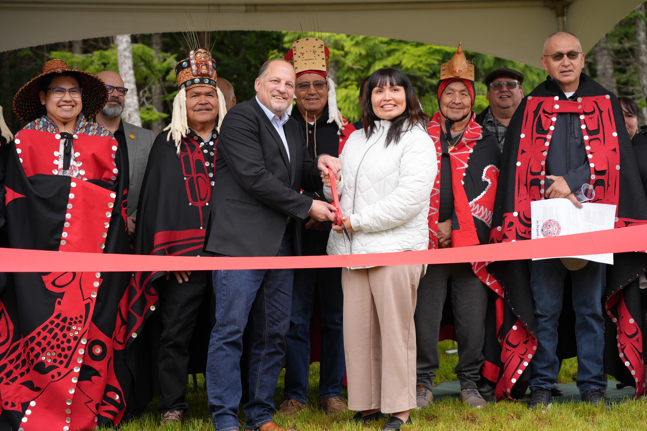 A man and woman cutting a red ribbon.